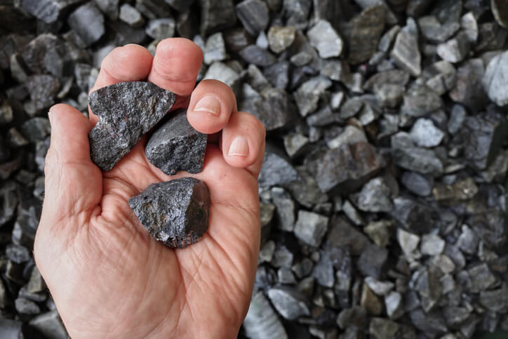 A hand holding a rundle rock, representing rundle rock vs. rundle fines for the best landscaping projects.