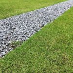 Drain rock installed in a landscaped drainage channel to improve water runoff, erosion control, and residential yard drainage performance.