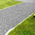 Limestone fines driveway bordered by green grass and landscape edging, providing a compacted, durable surface that enhances drainage and curb appeal for residential properties.