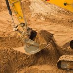 Excavator moving clay in construction during site preparation and earthwork.