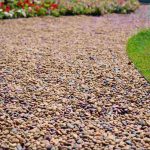 Tan rock landscaping material covering a pathway, showing decorative gravel used for outdoor landscaping and garden design.